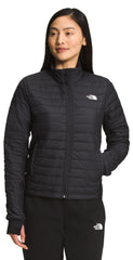 A woman wearing a black quilted jacket and black sweatpants.