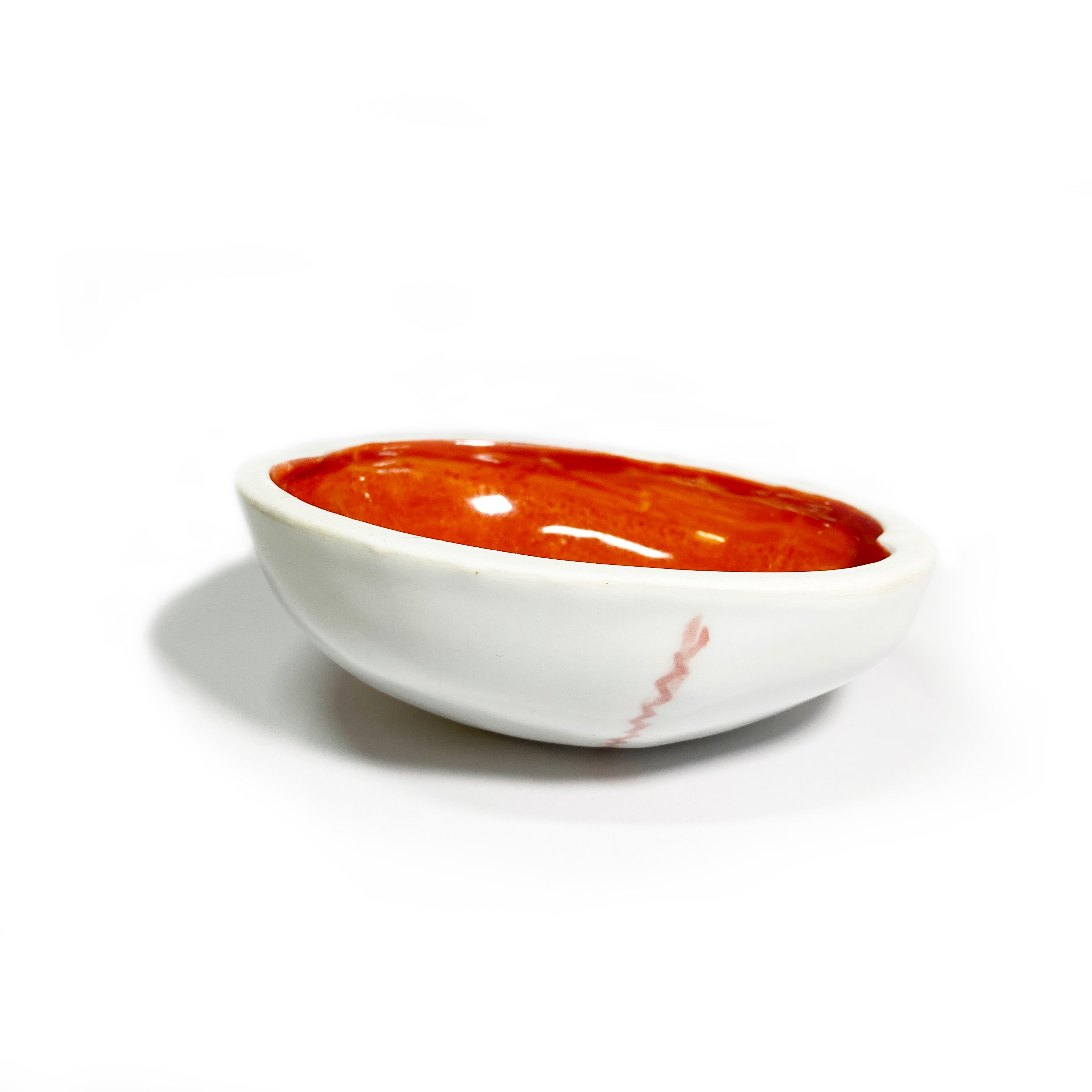 A porcelain skull-shaped cup kapala with a red interior and white exterior.