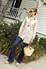 Woman wearing flax linen Christina top with jeans, beaded necklace, pewter bangles, and bag standing outside. --Arte Italica and Crown Linen Designs