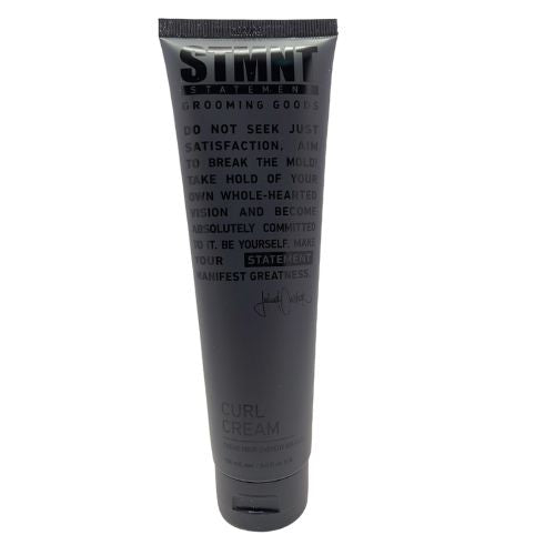 Tube noir STMNT Grooming Goods Curl Cream pour cheveux bouclés, crème coiffante végane à l’huile d’argan et cires végétales, présenté sur fond blanc.